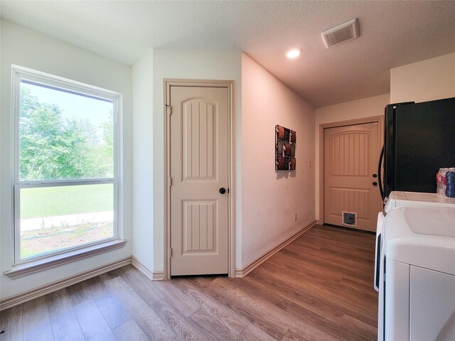 2755 Overlook Rd, Caldwell, TX 77836 - laundry area featuring washing machine and dryer, healthy amount of natural light, wood finished floors, a textured ceiling, and baseboards