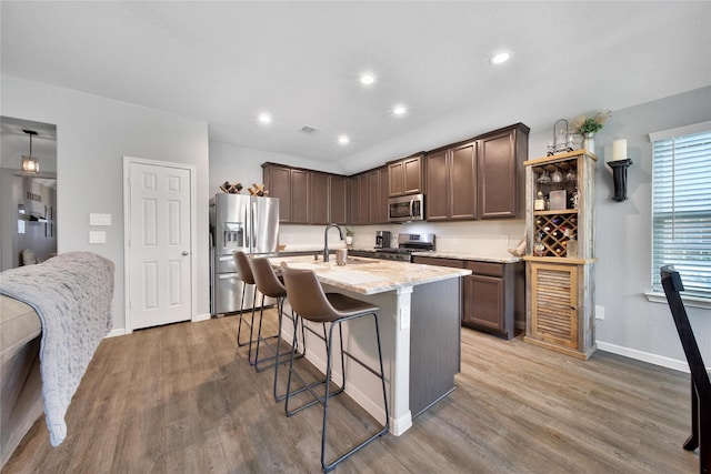 922 Golden Willow Ln, Conroe, TX 77304 - kitchen with stainless steel appliances, baseboards, a breakfast bar, light stone countertops, and light wood-style flooring