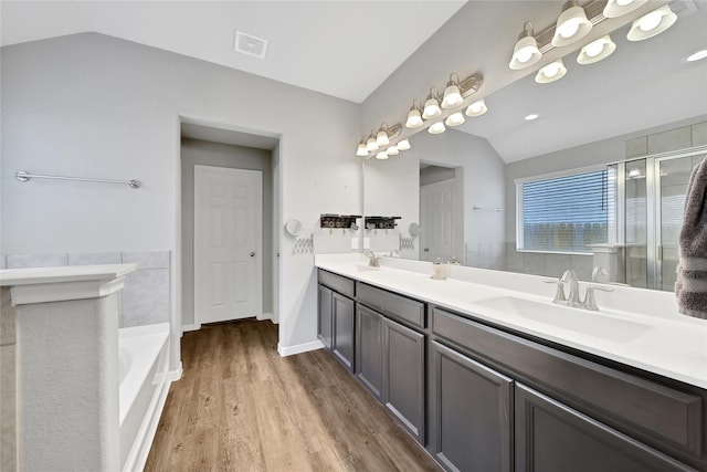 922 Golden Willow Ln, Conroe, TX 77304 - bathroom featuring vaulted ceiling, wood finished floors, double vanity, a bath, and a shower with door