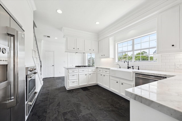 3007 Sackett St, Houston, TX 77098 - kitchen with appliances with stainless steel finishes, a peninsula, backsplash, white cabinets, and ornamental molding