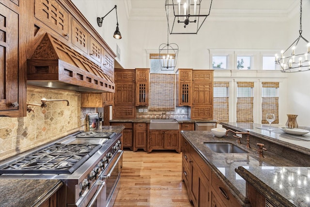 1010 Cortlandt St, Houston, TX 77008 - kitchen with a chandelier, appliances with stainless steel finishes, brown cabinetry, custom exhaust hood, and glass insert cabinets