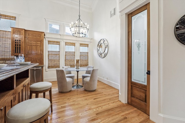 1010 Cortlandt St, Houston, TX 77008 - dining space featuring crown molding, light wood finished floors, a chandelier, and baseboards