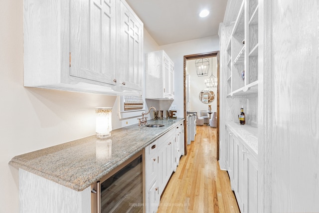 1010 Cortlandt St, Houston, TX 77008 - kitchen with wine cooler, a sink, white cabinets, light wood-style floors, and light stone countertops