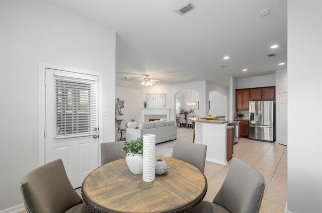 2414 Hannover Valley Ct, Spring, TX 77388 - dining room featuring arched walkways, ceiling fan, a tiled fireplace, light tile patterned flooring, and recessed lighting