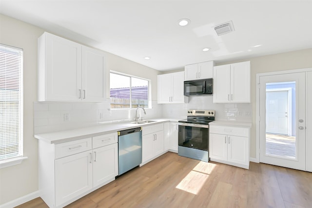 6334 Cambridge Glen Ln, Houston, TX 77035 - kitchen featuring stainless steel appliances, a sink, light wood finished floors, tasteful backsplash, and white cabinetry