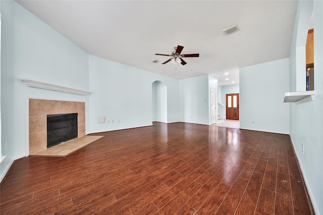 16655 Millridge Ln, Houston, TX 77095 - unfurnished living room with a tiled fireplace, wood finished floors, arched walkways, a ceiling fan, and baseboards