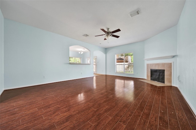 16655 Millridge Ln, Houston, TX 77095 - unfurnished living room featuring wood finished floors, a ceiling fan, a tiled fireplace, baseboards, and arched walkways