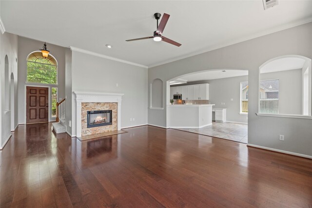 3427 Powell Way, Missouri City, TX 77459 - unfurnished living room featuring ceiling fan, wood-type flooring, crown molding, arched walkways, and baseboards