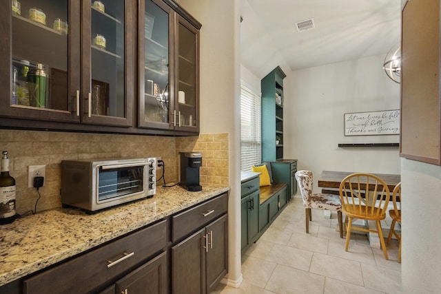 22078 Sun Haven Ln, Porter, TX 77365 - kitchen with dark brown cabinets, backsplash, light stone countertops, and light tile patterned floors