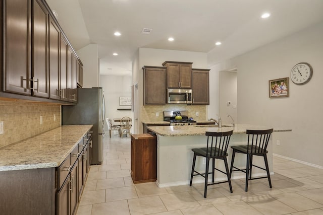 22078 Sun Haven Ln, Porter, TX 77365 - kitchen with appliances with stainless steel finishes, tasteful backsplash, dark brown cabinetry, a breakfast bar, and recessed lighting