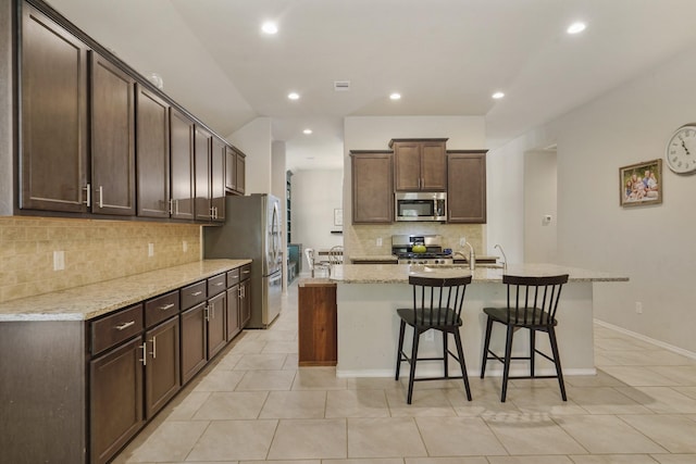 22078 Sun Haven Ln, Porter, TX 77365 - kitchen with stainless steel appliances, tasteful backsplash, a breakfast bar, light tile patterned floors, and recessed lighting