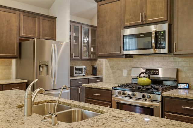 22078 Sun Haven Ln, Porter, TX 77365 - kitchen with appliances with stainless steel finishes, a sink, light stone counters, glass insert cabinets, and dark brown cabinets