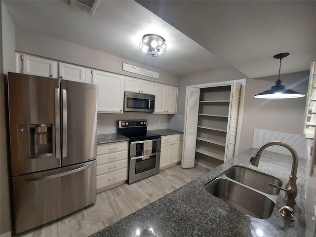 2356 Gemini St, Houston, TX 77058 - kitchen with stainless steel appliances, a sink, white cabinets, and hanging light fixtures