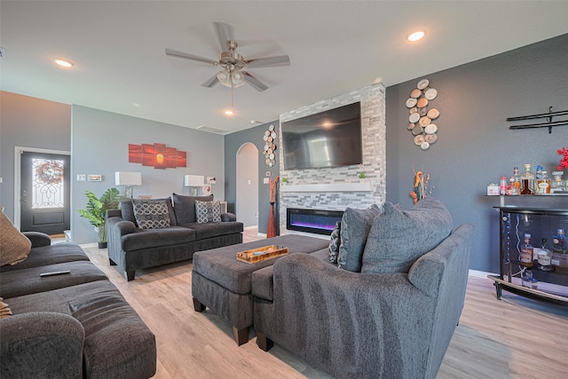 10027 Yanet Grove Ln, Houston, TX 77044 - living room with a ceiling fan, a large fireplace, wood finished floors, arched walkways, and recessed lighting