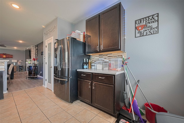 10027 Yanet Grove Ln, Houston, TX 77044 - kitchen with stainless steel fridge with ice dispenser, dark brown cabinets, light tile patterned flooring, light countertops, and decorative backsplash