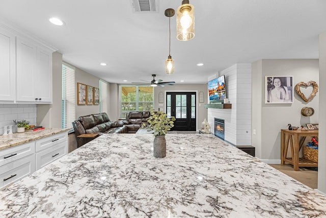 4439 W Bayshore Rd, Anahuac, TX 77514 - kitchen with a fireplace, light stone countertops, a ceiling fan, open floor plan, and white cabinetry