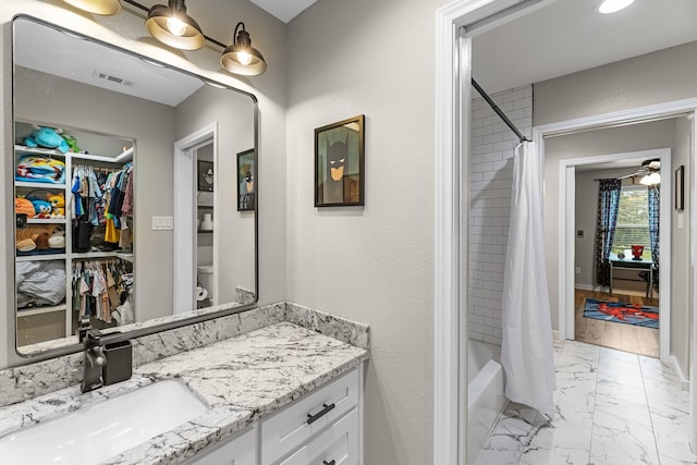 4439 W Bayshore Rd, Anahuac, TX 77514 - full bathroom featuring vanity, marble look tiles, shower / bathtub combination with curtain, and a spacious closet