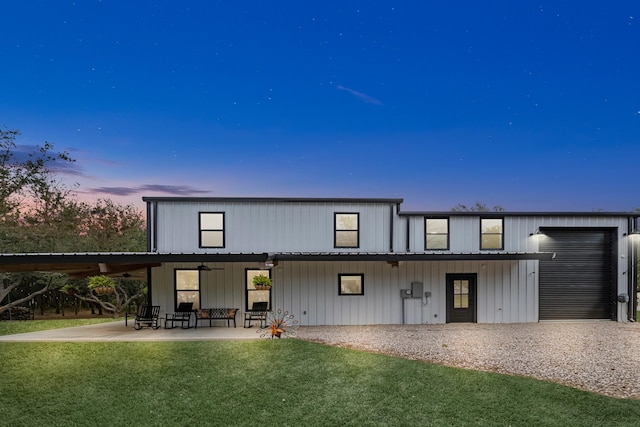 4439 W Bayshore Rd, Anahuac, TX 77514 - back of property at dusk with a lawn, a ceiling fan, a patio, and a garage