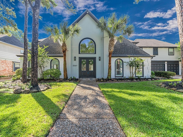 20647 Laurel Lock Dr, Katy, TX 77450 - view of front of home with french doors, roof with shingles, brick siding, a front lawn, and stucco siding