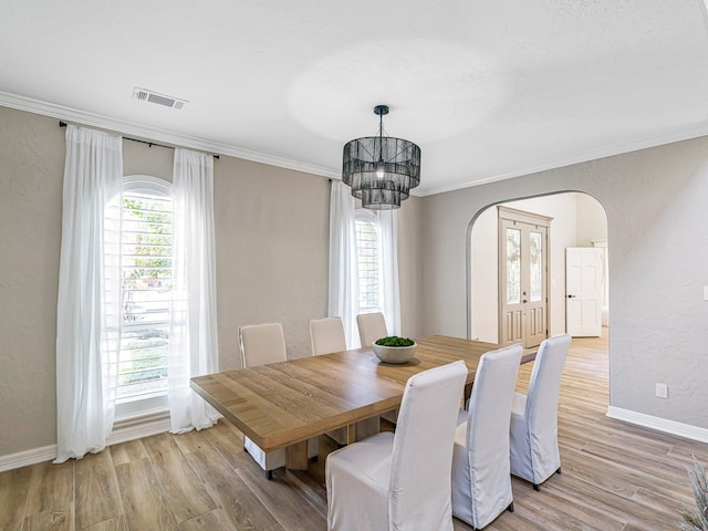 20647 Laurel Lock Dr, Katy, TX 77450 - dining area featuring arched walkways, light wood finished floors, ornamental molding, baseboards, and a chandelier