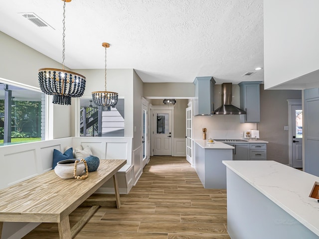 20647 Laurel Lock Dr, Katy, TX 77450 - kitchen with wall chimney exhaust hood, light wood-style flooring, a chandelier, gray cabinets, and a textured ceiling