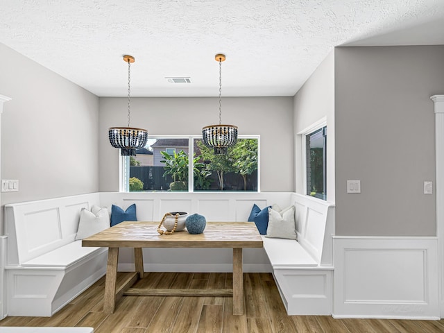 20647 Laurel Lock Dr, Katy, TX 77450 - dining room featuring breakfast area, a chandelier, wood finished floors, wainscoting, and a decorative wall