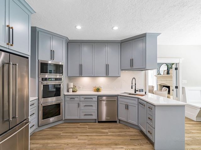 20647 Laurel Lock Dr, Katy, TX 77450 - kitchen with appliances with stainless steel finishes, gray cabinetry, a peninsula, a sink, and light countertops