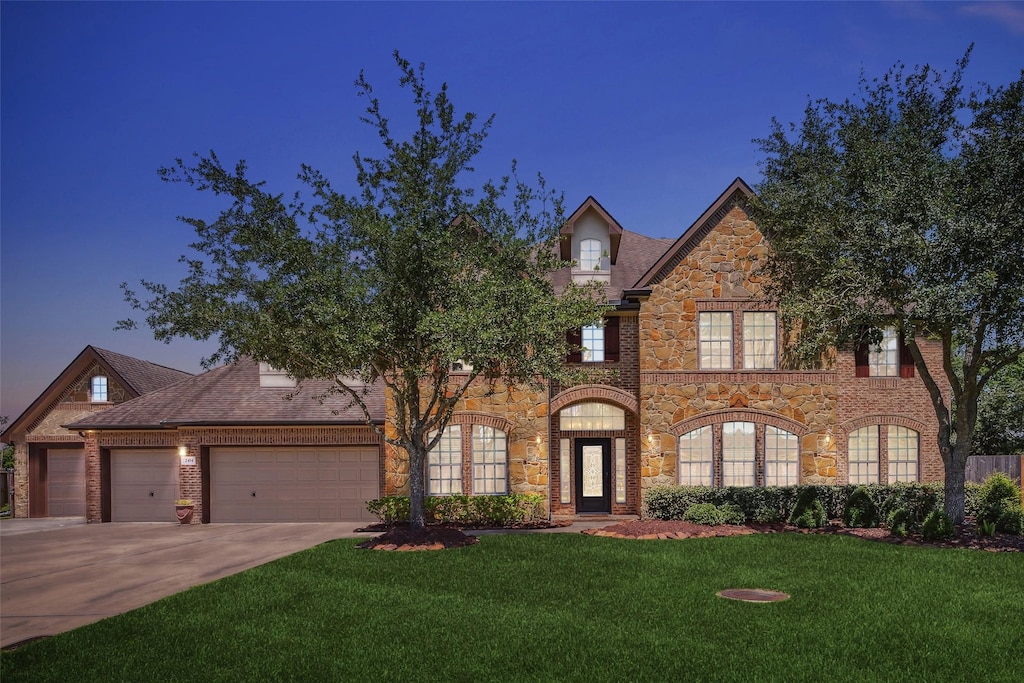 2414 Lakeway Dr, Friendswood, TX 77546 - view of front of house with stone siding, a front lawn, driveway, and an attached garage