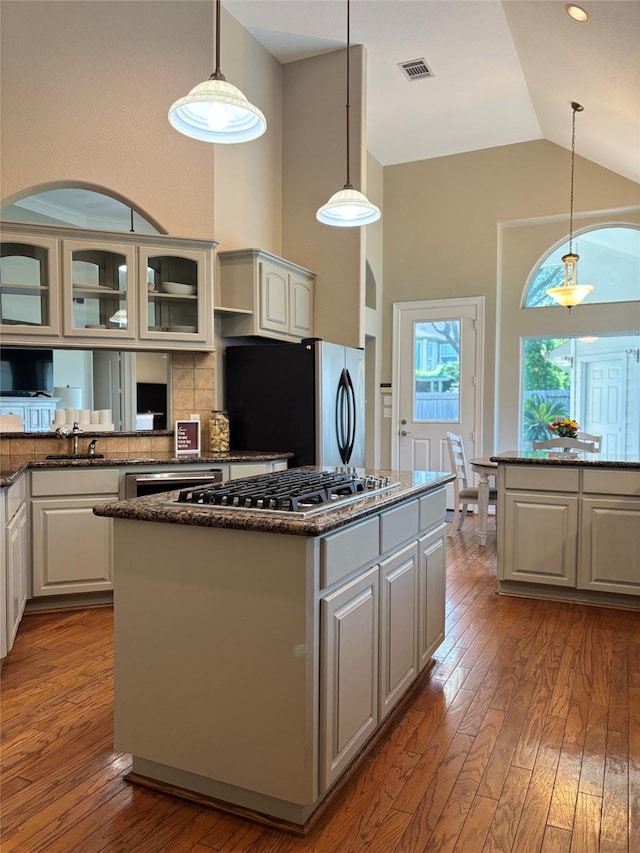 2331 Scottsdale Ct, League City, TX 77573 - kitchen with stainless steel appliances, a center island, hardwood / wood-style flooring, glass insert cabinets, and high vaulted ceiling