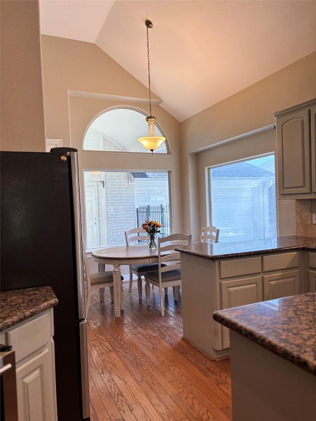 2331 Scottsdale Ct, League City, TX 77573 - kitchen with freestanding refrigerator, vaulted ceiling, light wood finished floors, decorative light fixtures, and dark stone countertops