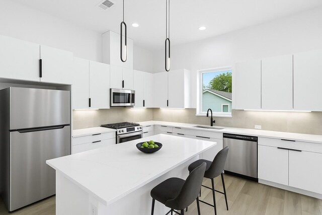 5203 San Juan St, Houston, TX 77020 - kitchen with appliances with stainless steel finishes, a sink, a center island, a breakfast bar, and white cabinetry