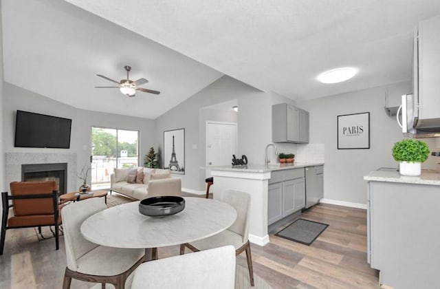 10101 S Gessner Rd Unit 811, Houston, TX 77071 - dining space with light wood-style floors, baseboards, lofted ceiling, a ceiling fan, and a high end fireplace