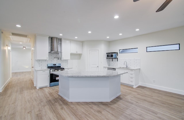1853 Lombardy St, Houston, TX 77023 - kitchen featuring appliances with stainless steel finishes, wall chimney exhaust hood, a sink, backsplash, and light wood-style floors
