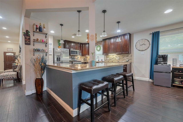 3207 Pheasant Trail Dr, Sugar Land, TX 77498 - kitchen featuring stainless steel appliances, a sink, light stone counters, baseboards, and a breakfast bar area