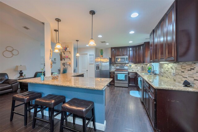 3207 Pheasant Trail Dr, Sugar Land, TX 77498 - kitchen featuring appliances with stainless steel finishes, a sink, dark brown cabinets, a breakfast bar area, and recessed lighting