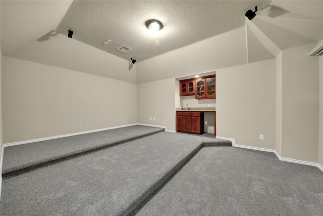 2108 Asbury Ct, Pearland, TX 77581 - additional living space with dark carpet, a textured ceiling, baseboards, and bar area