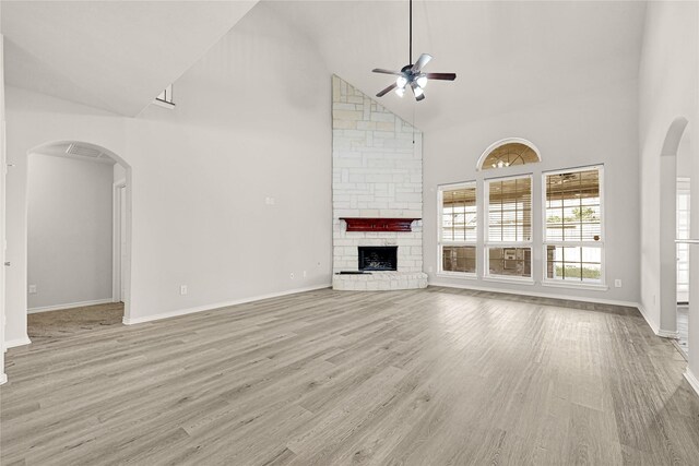 2108 Asbury Ct, Pearland, TX 77581 - unfurnished living room featuring high vaulted ceiling, a ceiling fan, a stone fireplace, baseboards, and light wood-type flooring