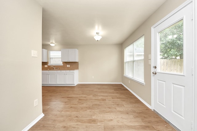 5043 Canyon Blanco Dr, Houston, TX 77045 - unfurnished living room featuring plenty of natural light, baseboards, a sink, and light wood-style flooring