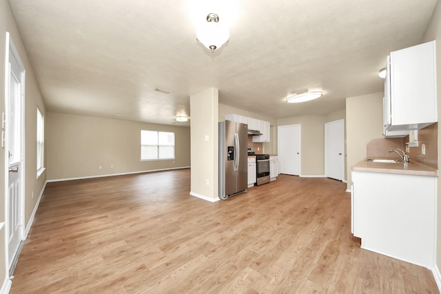 5043 Canyon Blanco Dr, Houston, TX 77045 - kitchen with appliances with stainless steel finishes, open floor plan, a sink, white cabinets, and light wood finished floors