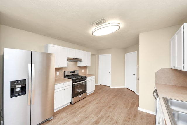 5043 Canyon Blanco Dr, Houston, TX 77045 - kitchen featuring stainless steel appliances, under cabinet range hood, light countertops, and white cabinetry
