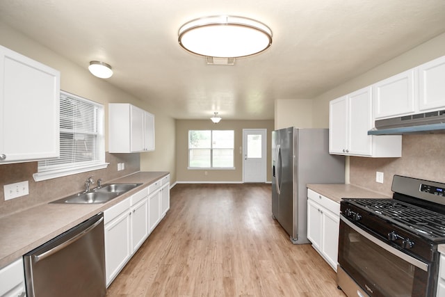 5043 Canyon Blanco Dr, Houston, TX 77045 - kitchen with stainless steel appliances, under cabinet range hood, a sink, light wood finished floors, and backsplash