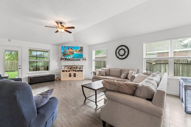 living room featuring ceiling fan, wood finished floors, and vaulted ceiling