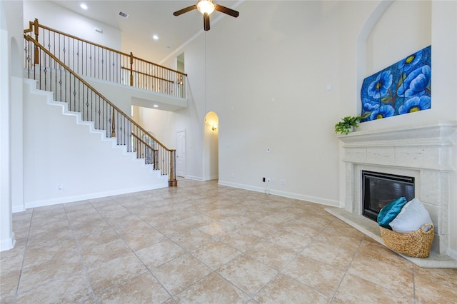 28015 Heritage Stream Dr, Katy, TX 77494 - unfurnished living room with ceiling fan, a towering ceiling, stairway, a high end fireplace, and arched walkways