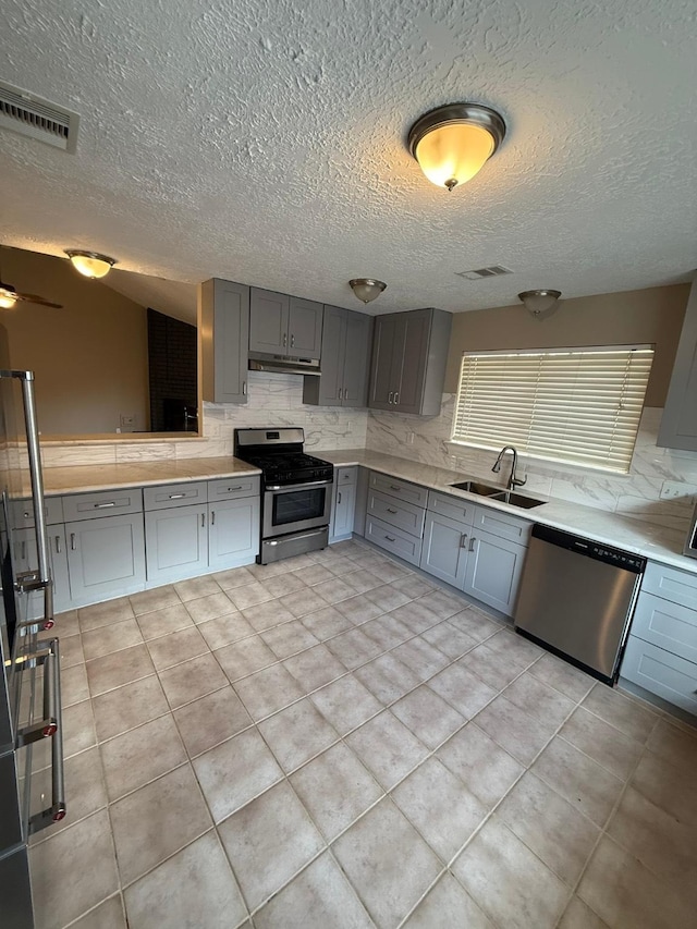 2614 Sicklepod Dr, Houston, TX 77084 - kitchen with appliances with stainless steel finishes, a sink, gray cabinetry, decorative backsplash, and a textured ceiling