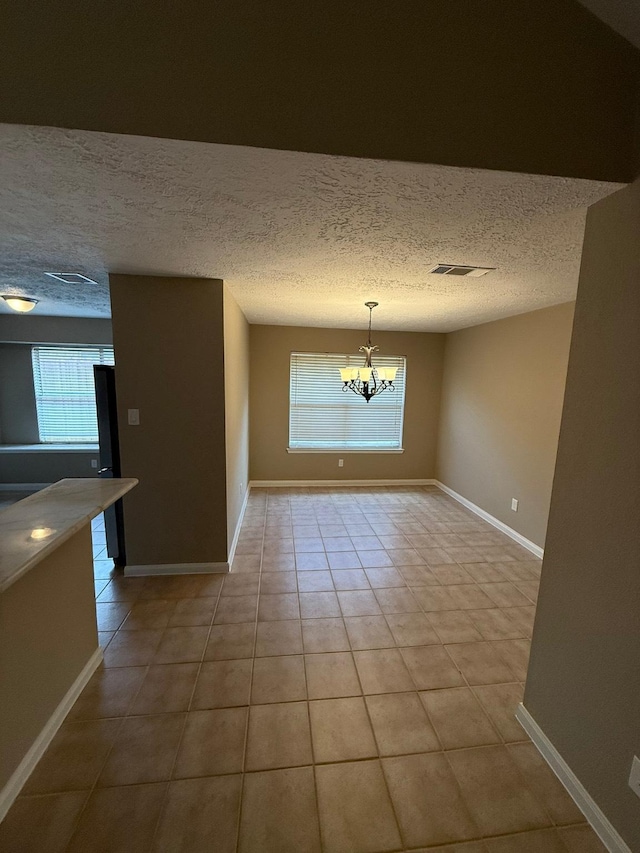 2614 Sicklepod Dr, Houston, TX 77084 - unfurnished dining area featuring plenty of natural light, a chandelier, light tile patterned floors, baseboards, and a textured ceiling