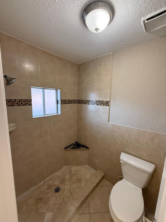 2614 Sicklepod Dr, Houston, TX 77084 - bathroom with tiled shower, tile walls, toilet, a textured ceiling, and tile patterned floors