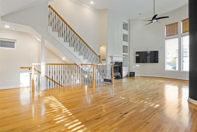 unfurnished living room featuring built in shelves, a ceiling fan, wood finished floors, a fireplace, and recessed lighting