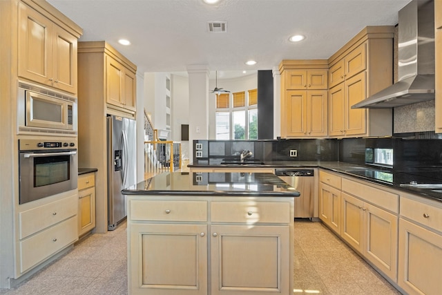 kitchen featuring appliances with stainless steel finishes, wall chimney exhaust hood, dark countertops, light brown cabinets, and recessed lighting
