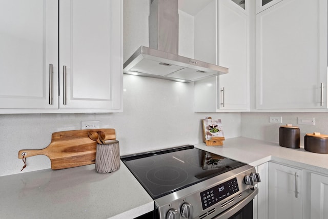 651 Bering Dr Unit 1406, Houston, TX 77057 - kitchen featuring wall chimney exhaust hood, stainless steel electric stove, and white cabinetry