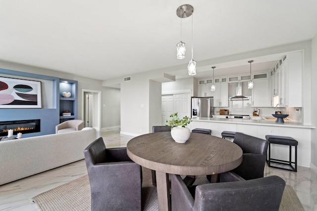651 Bering Dr Unit 1406, Houston, TX 77057 - dining space with light marble finish flooring, built in features, baseboards, and a glass covered fireplace